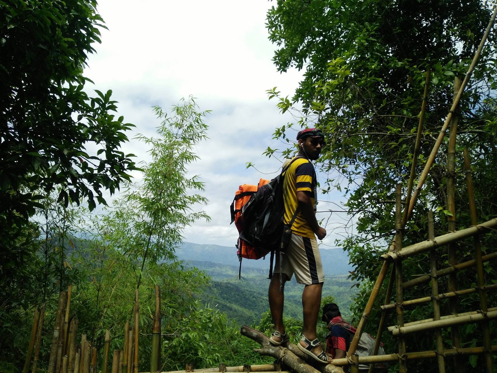 Standing on a bamboo walkway on a forested ridge, hills receding into cloud behind
